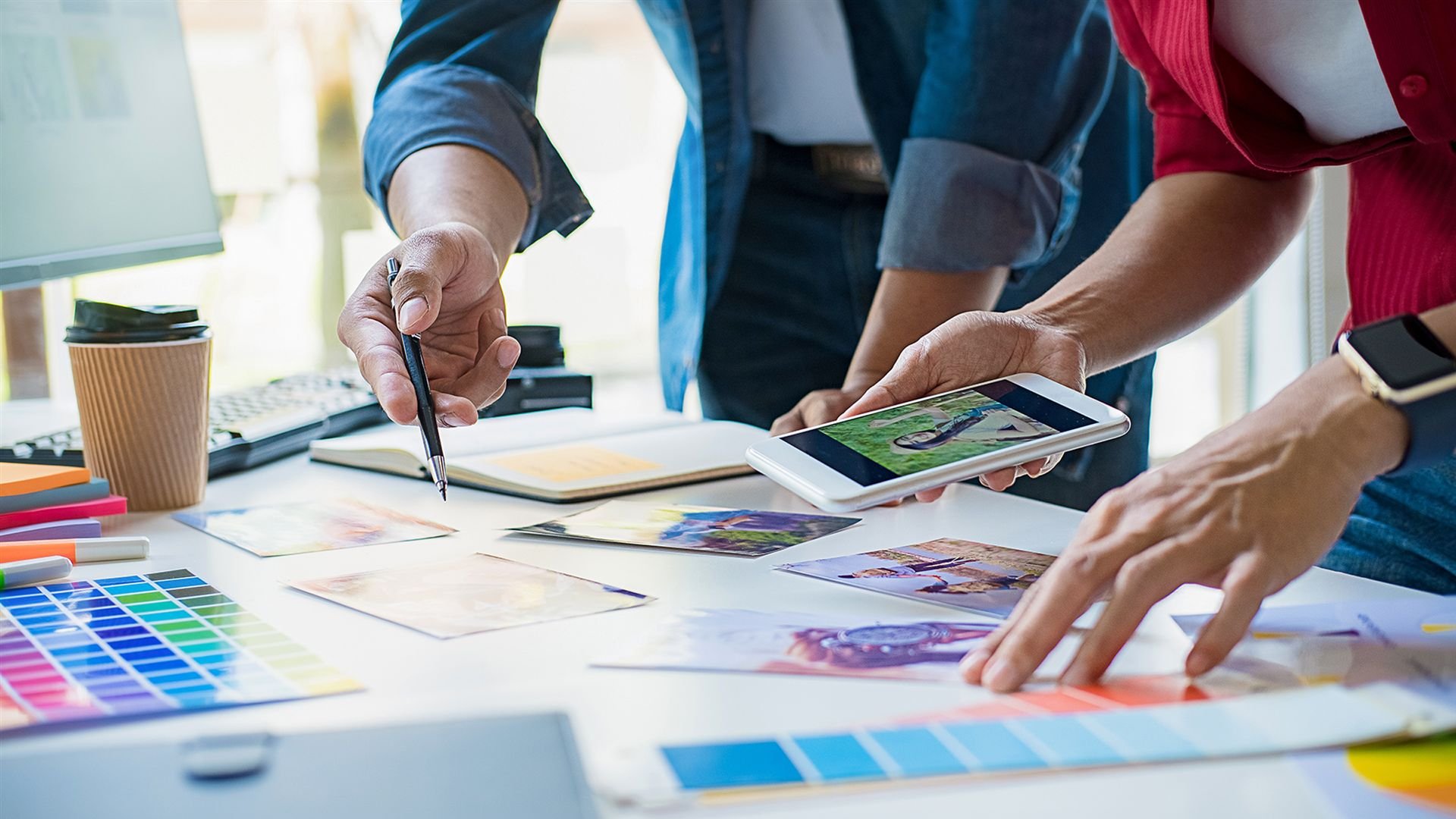 Zwei Personen arbeiten an einem Designprojekt und besprechen Entwürfe vor einem Tablet.